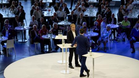 Ministerpräsident Daniel Günther und Moderator Christopher Scheffelmeier stehen auf einer Bühne.
